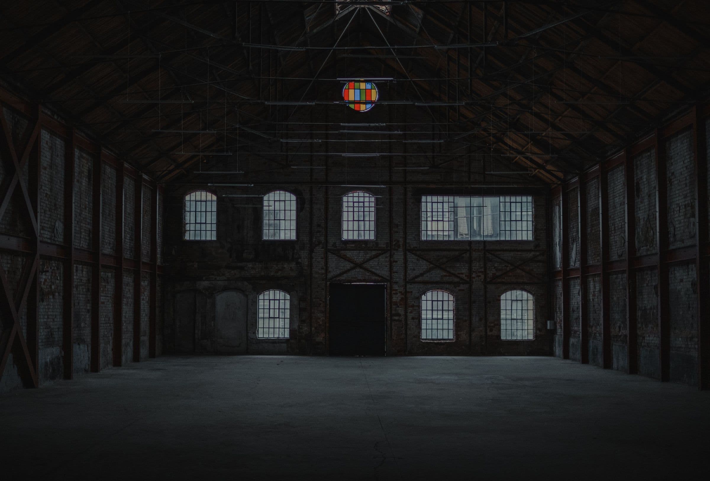 The retained brick hall under the original roof trusses, stained-glass roundel reinstated